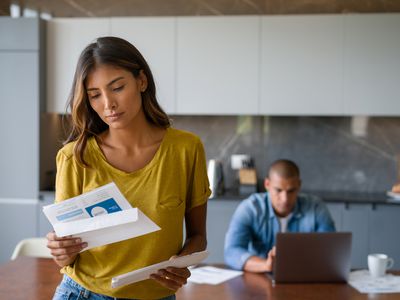 A woman looks concerned as she reads paperwork.