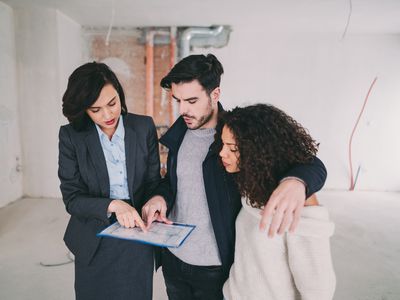 Real estate agent showing condo for sale to young couple