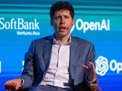 Sam Altman CEO of OpenAI, sitting on a podium with OpenAI sign behind him