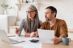 Couple looking at paperwork and a laptop at home