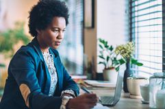 Woman holding a pen and looking at a laptop