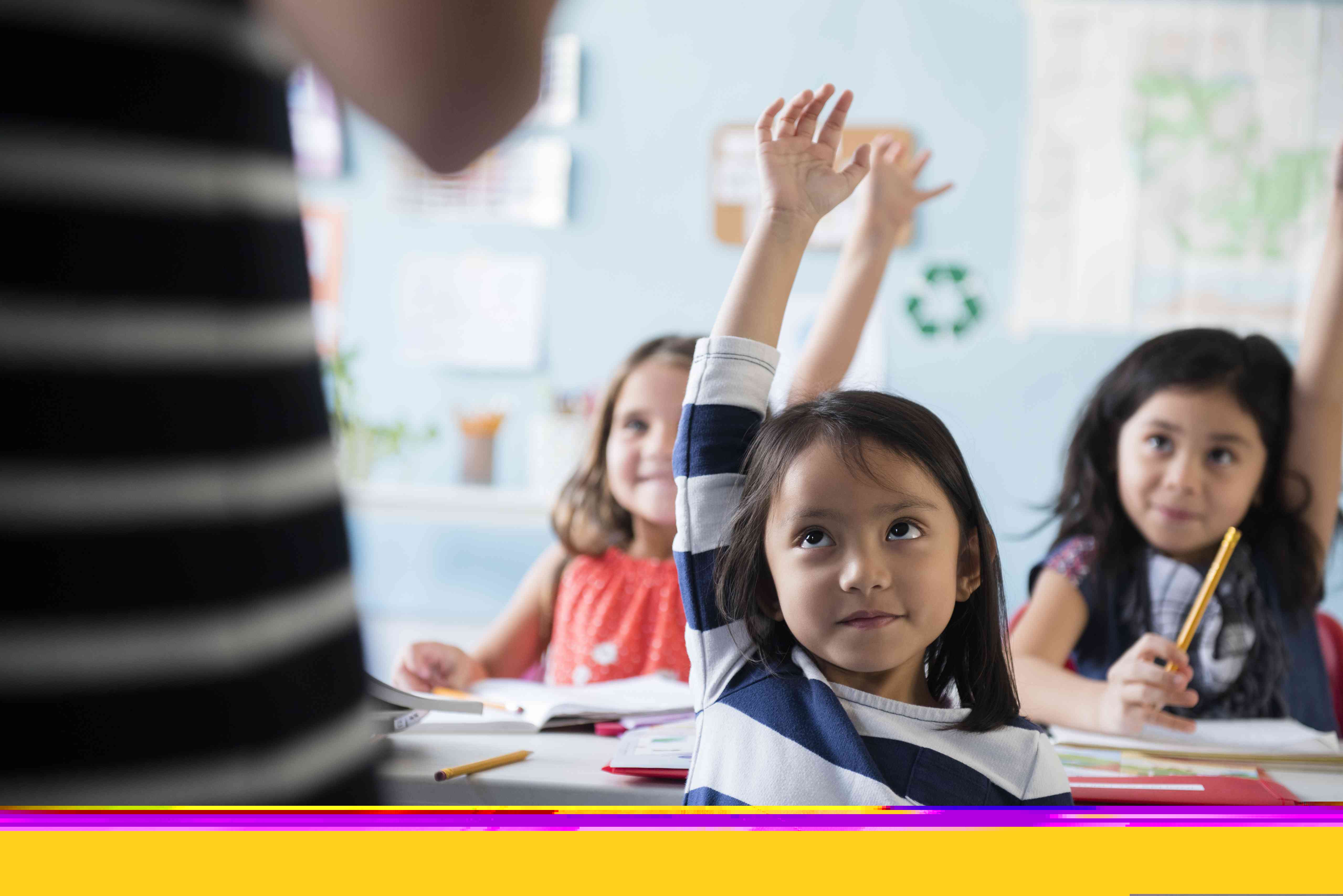 Girls raising hand for teacher in classroom