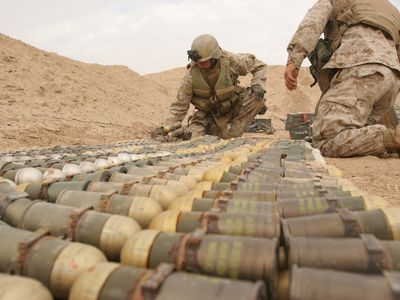 U.S. Marine Corps and U.S. Army explosive ordnance disposal technicians arrange unexploded ordnance for demolition