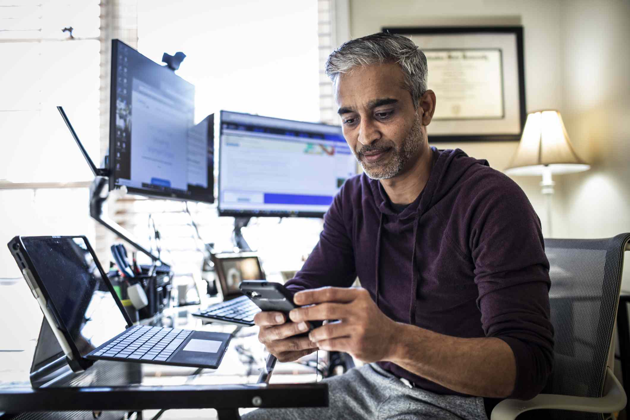 A man looks at his phone in his home office