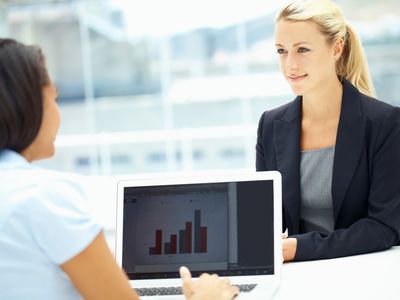 Two young executives having a meeting while working on a laptop.