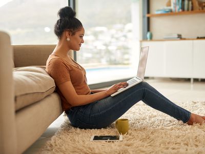 Young woman sitting in her living room and doing her online banking on a laptop