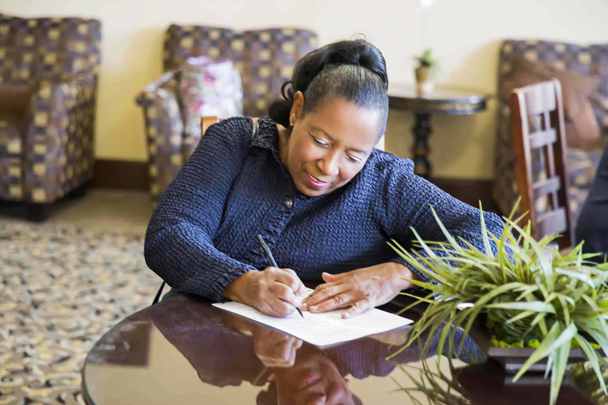 A woman fills out an application at a table.