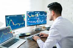 Hispanic young male stock trader typing on keyboard while using computer at home