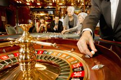 Close up of roulette wheel in a fancy casino with people betting in the background