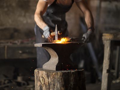 Blacksmith manually forging the molten metal