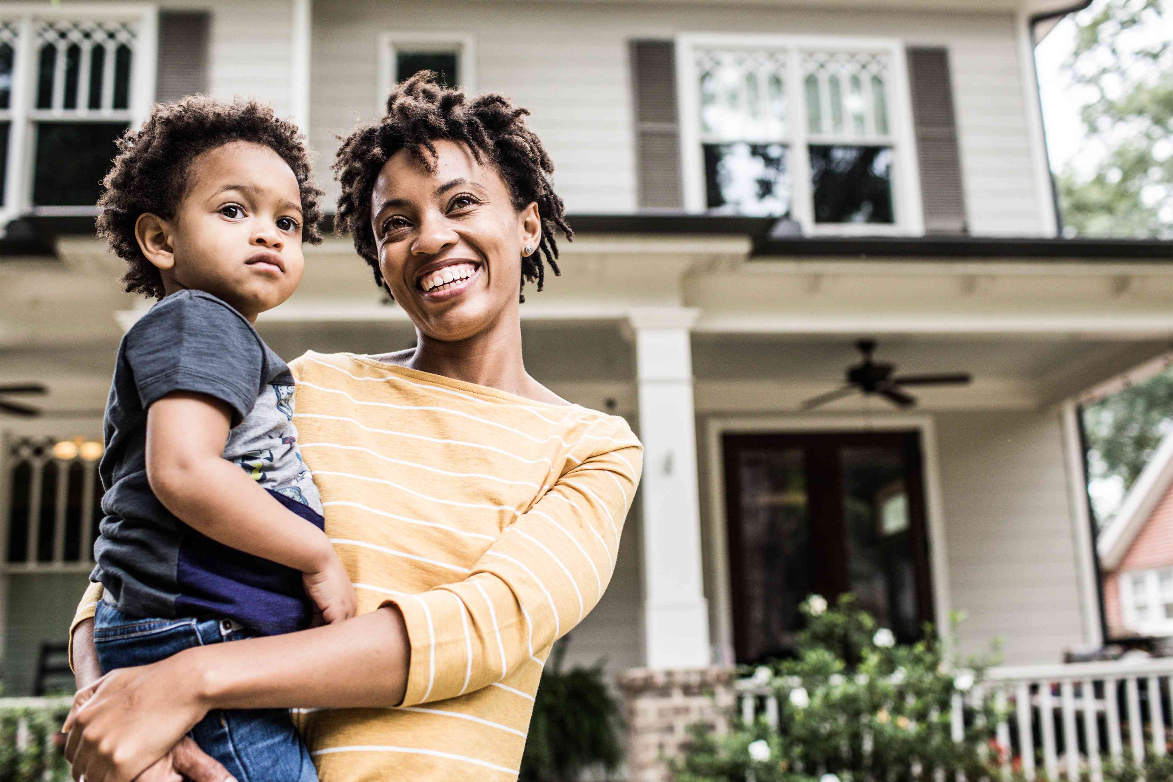 Portrait of mother and daughter in front of home