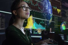 A stock trader reviews stock market data on a monitor