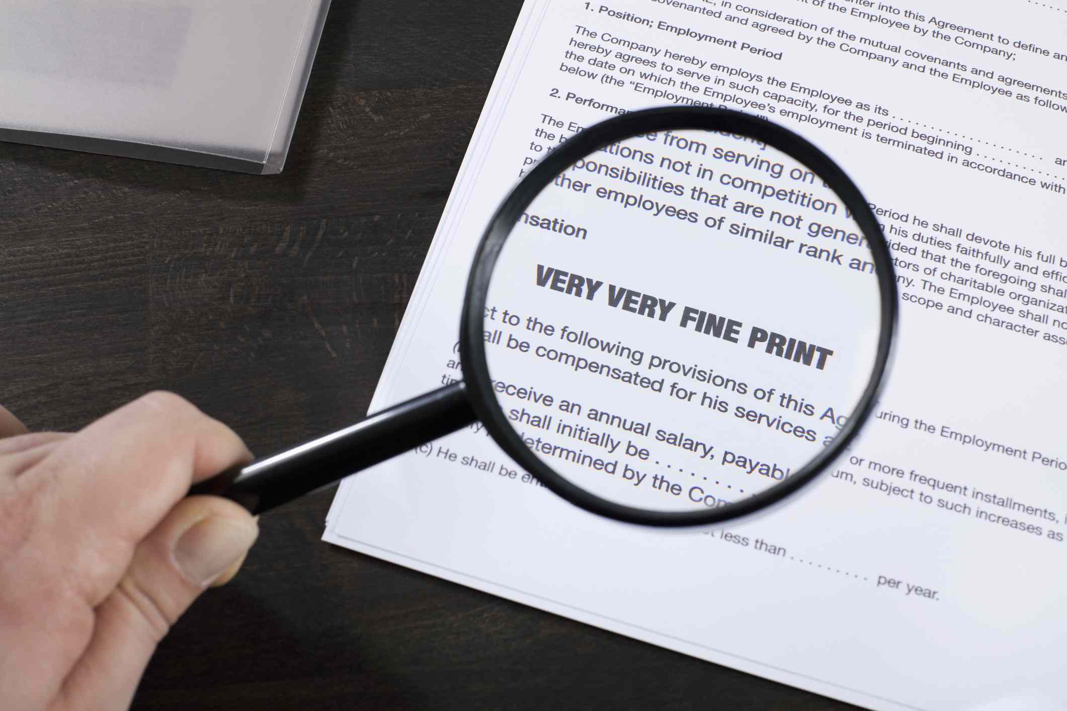 Magnifying glass over a paper that shows text that reads "very very fine print."