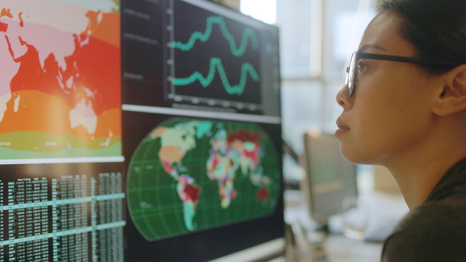 An analyst looks at screens displaying population demographic and statistics data to determine the change in population over time.