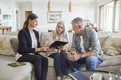 Female financial advisor is with couple in a living room.