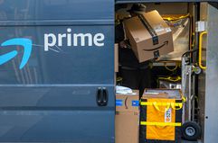 A worker sorts boxes inside an Amazon delivery van.