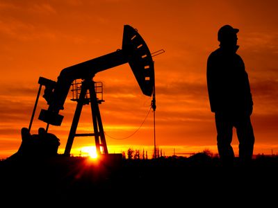 An oil field worker stands near a pump in Alberta, Canada.