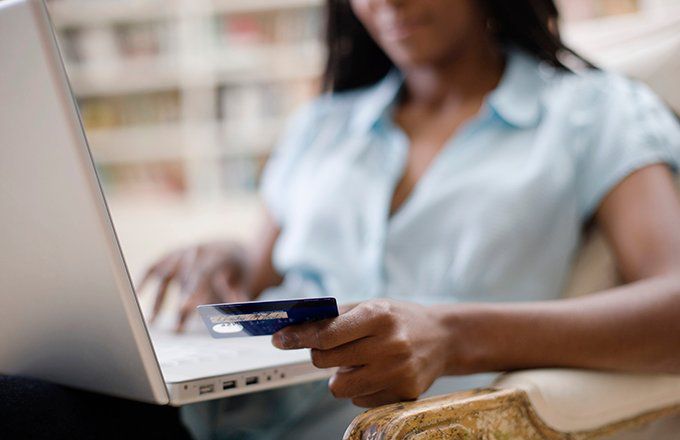 Woman holding credit card while using a laptop computer