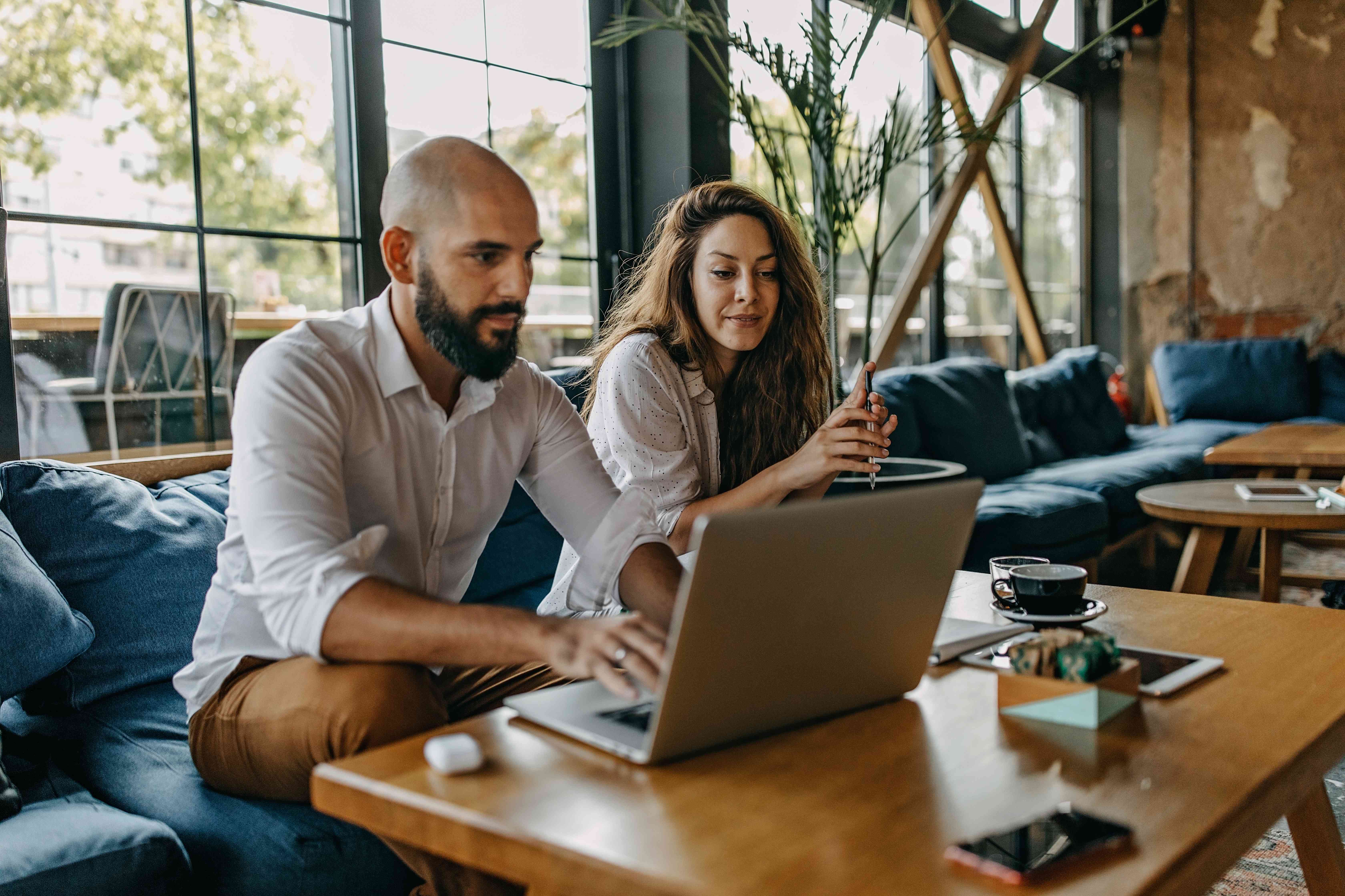 Couple in their 30s sitting in their living room and looking at a laptop together