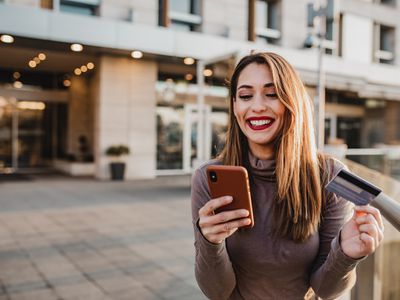 Woman paying with a credit card on her phone outside of a building