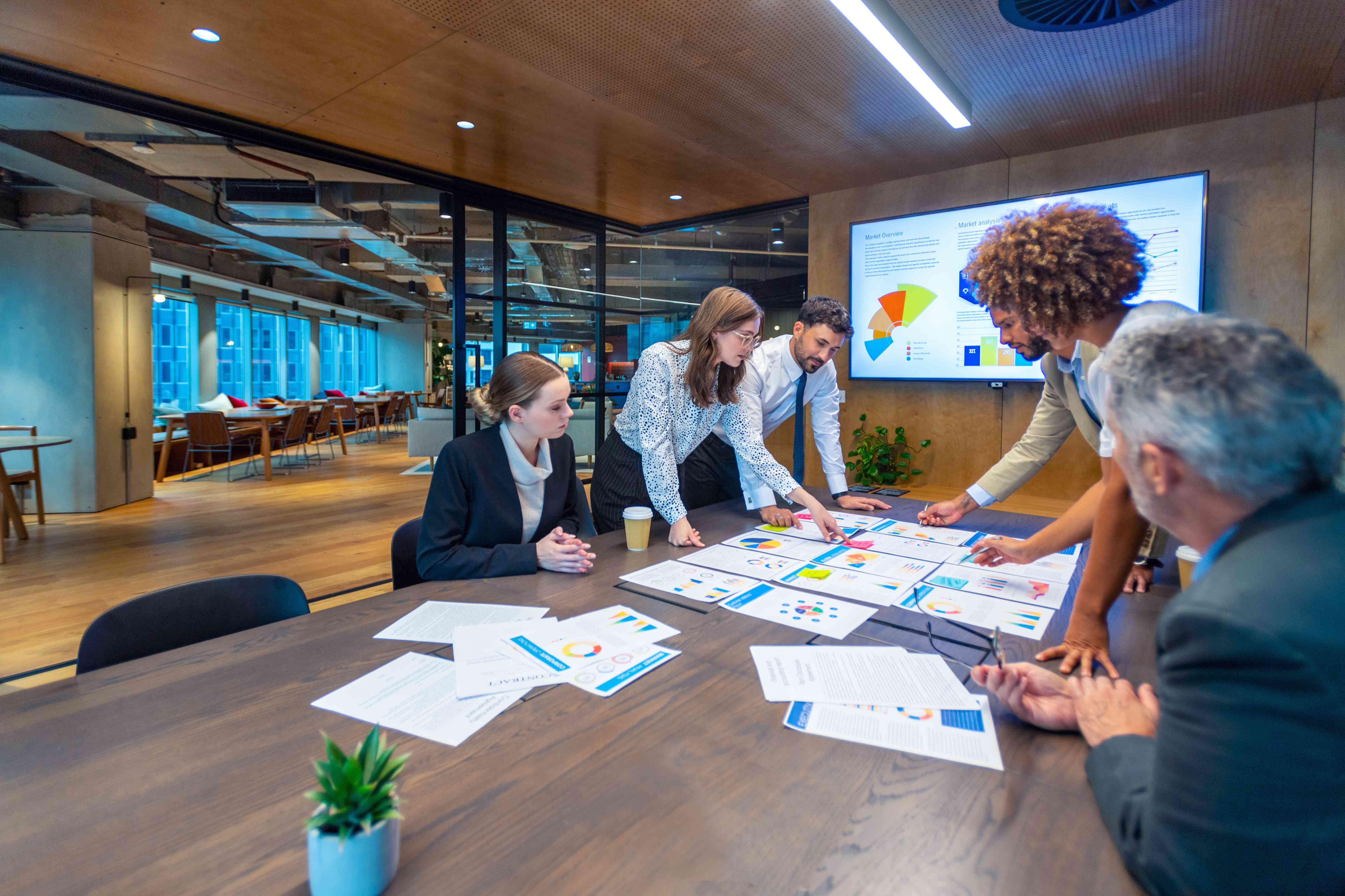 Paperwork and group of peoples hands on a board room table at a business presentation or seminar