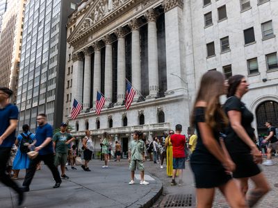 Several people walk past outside the New York Stock Exchange building, where three American flags are on display.