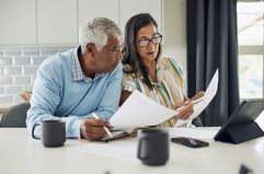 A couple reviews their finances together at the kitchen table. 