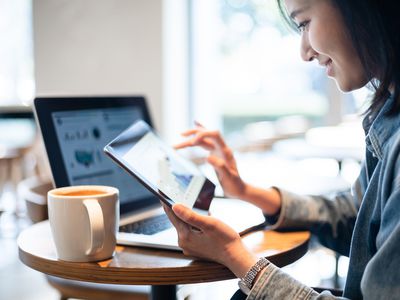 A young investor reviews investments on a laptop and tablet