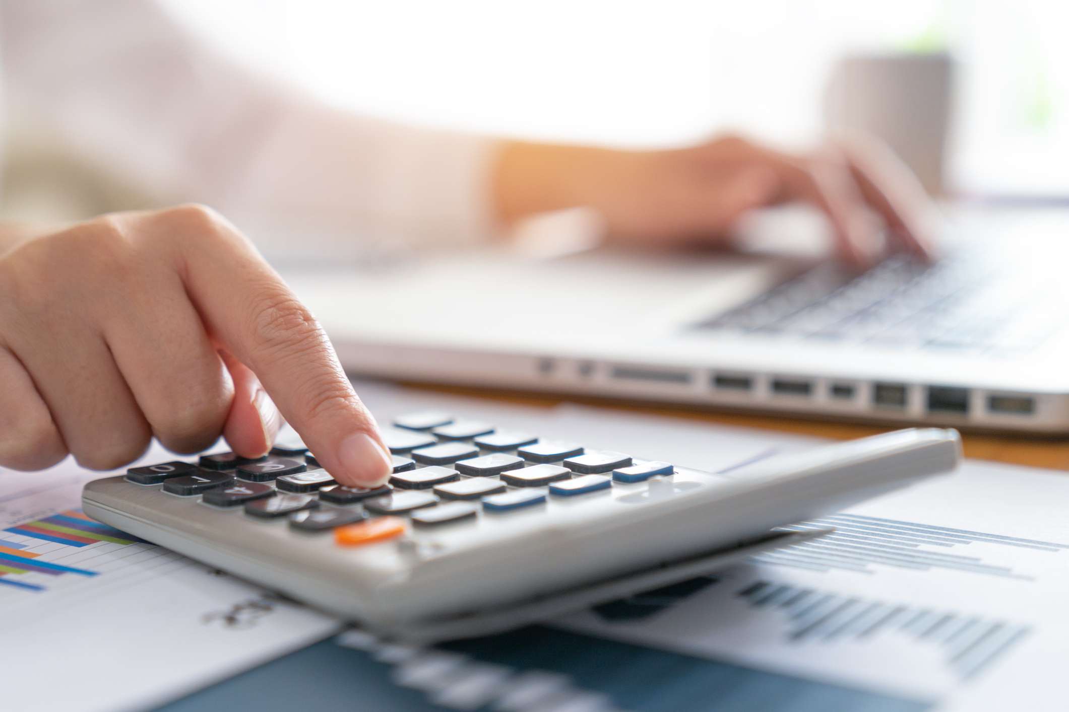 A businesswoman using a calculator and a laptop.