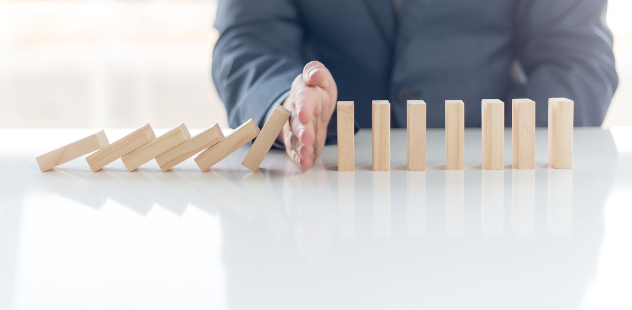 Businessman stopping domino effect.