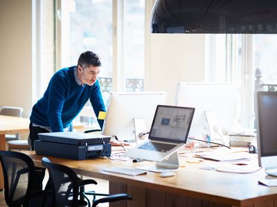 Small Business Start up owner standing by desk working on a computer for a SBA loan