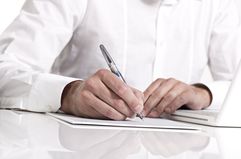 Businessman holding a pen and taking notes on paper.