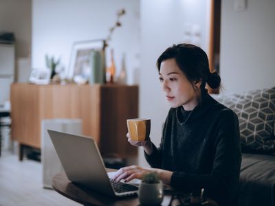 Busy concentrated young Asian woman working from home, working on laptop till late in the evening at home. Home office, overworked, deadline and lifestyle concept