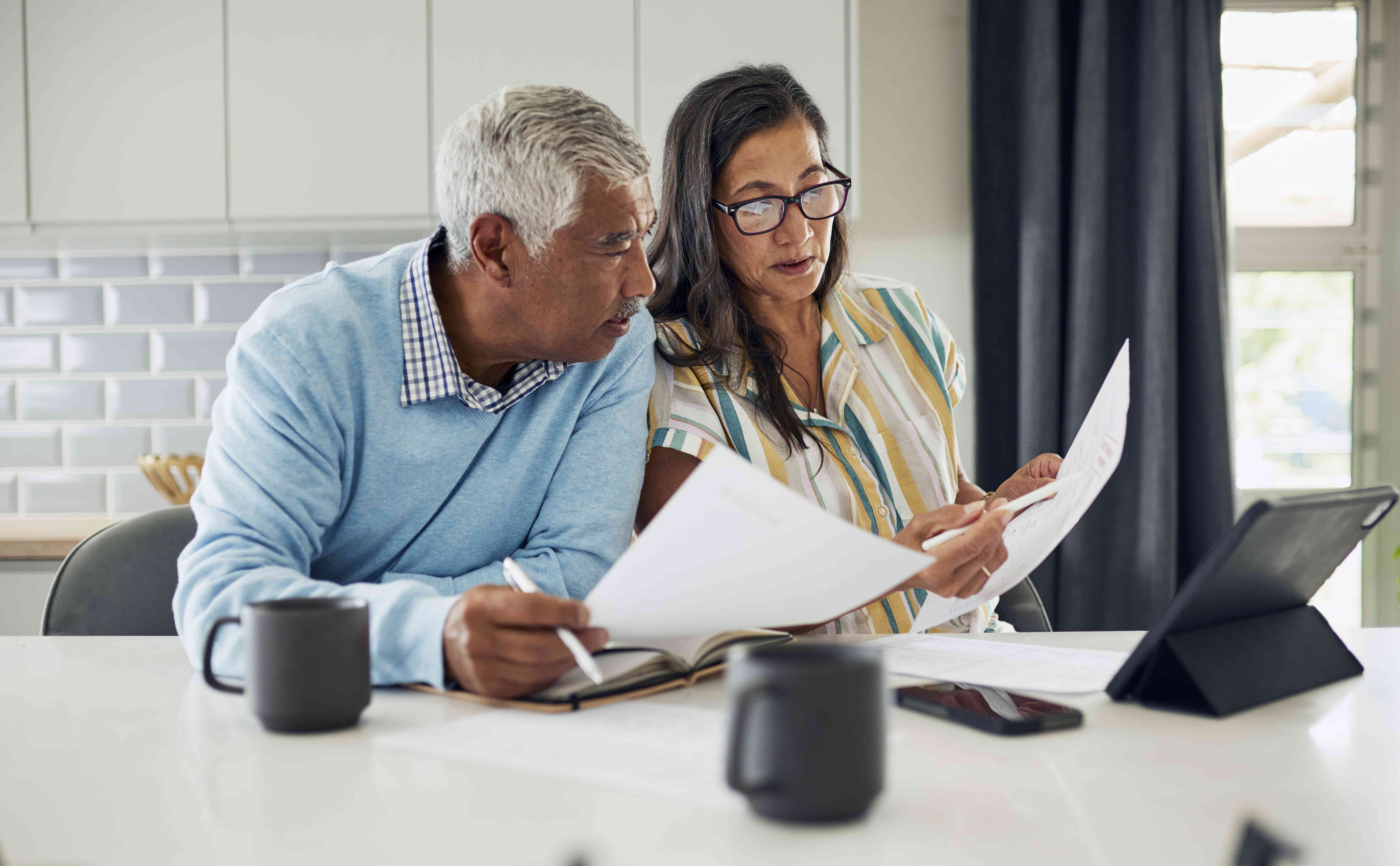 A couple reviews their finances together at the kitchen table. 