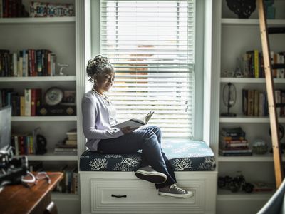 Mature woman on window seat reading a book