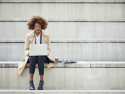 Young businessperson using laptop while sitting on steps. 