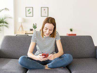 Relaxed young adult woman with cell phone to check savings account