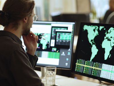 Young man sitting before a computer monitor showing a map of the world