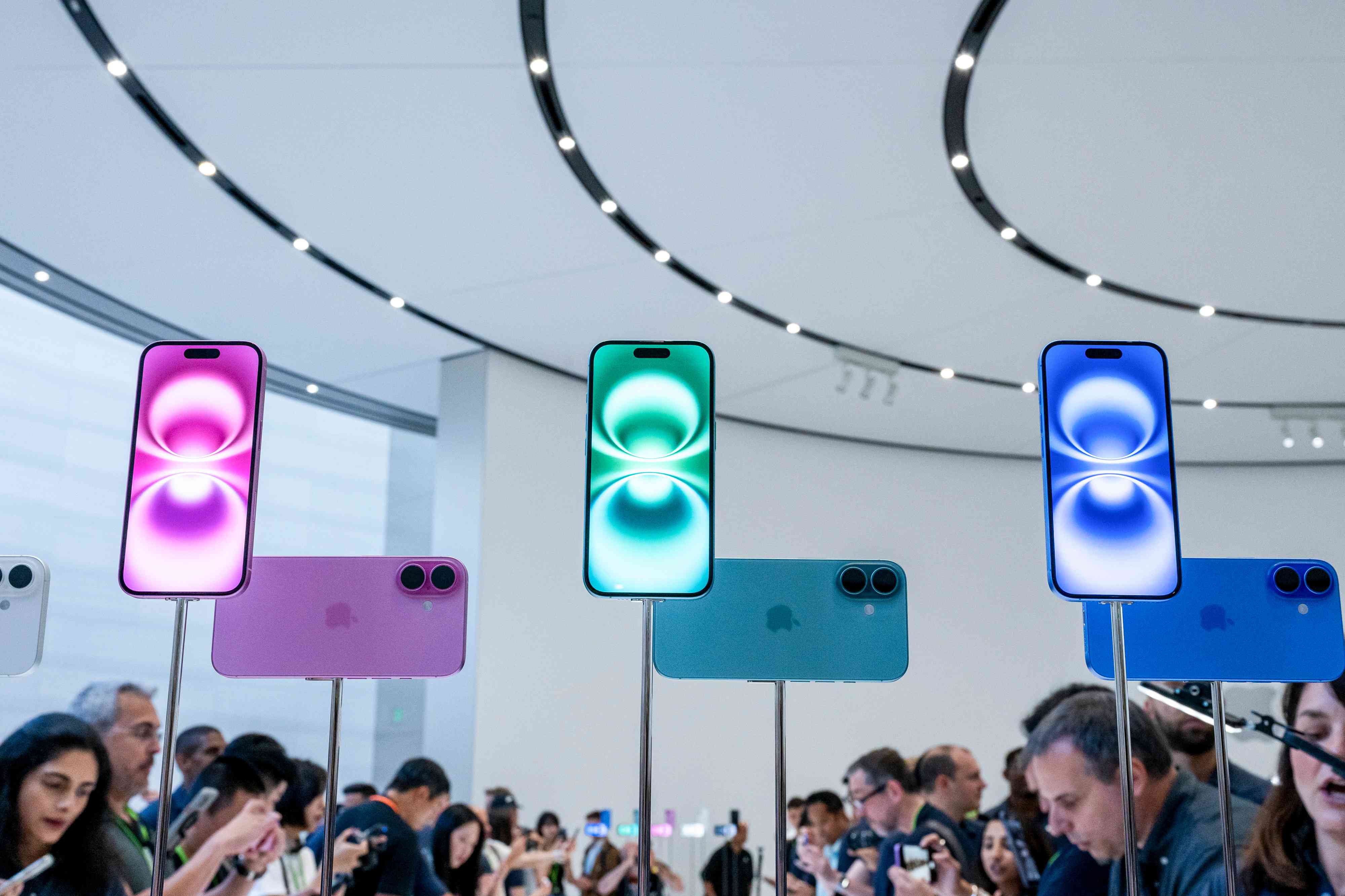 Blue, pink, and green versions of the iPhone 16 is displayed at an event at Apple's California headquarters.