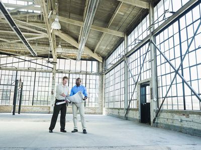 Businessmen reading blueprints in empty warehouse Real Estate Crowdfunding Sites