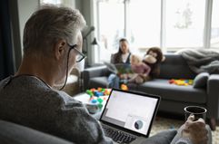 Senior man using laptop and drinking coffee in living room