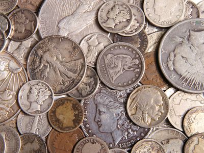 A close-up of a collection of antique silver coins lay spread out on a surface