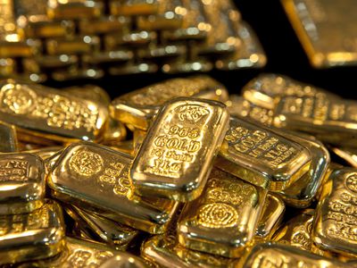 A closeup of gold bullion bars laying in a pile on a surface. 