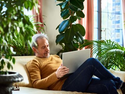 Mature man sitting on sofa using laptop