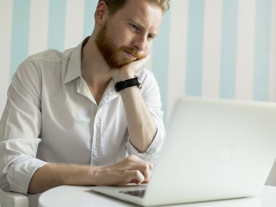 Young man in his 20s pondering something on his laptop screen