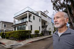 Man standing in the foreground of a residential property in background.