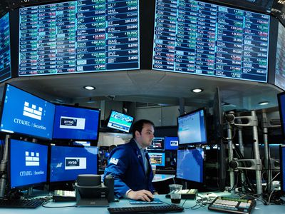 A trader works on the floor of the New York Stock Exchange surrounded by screens with stock market data