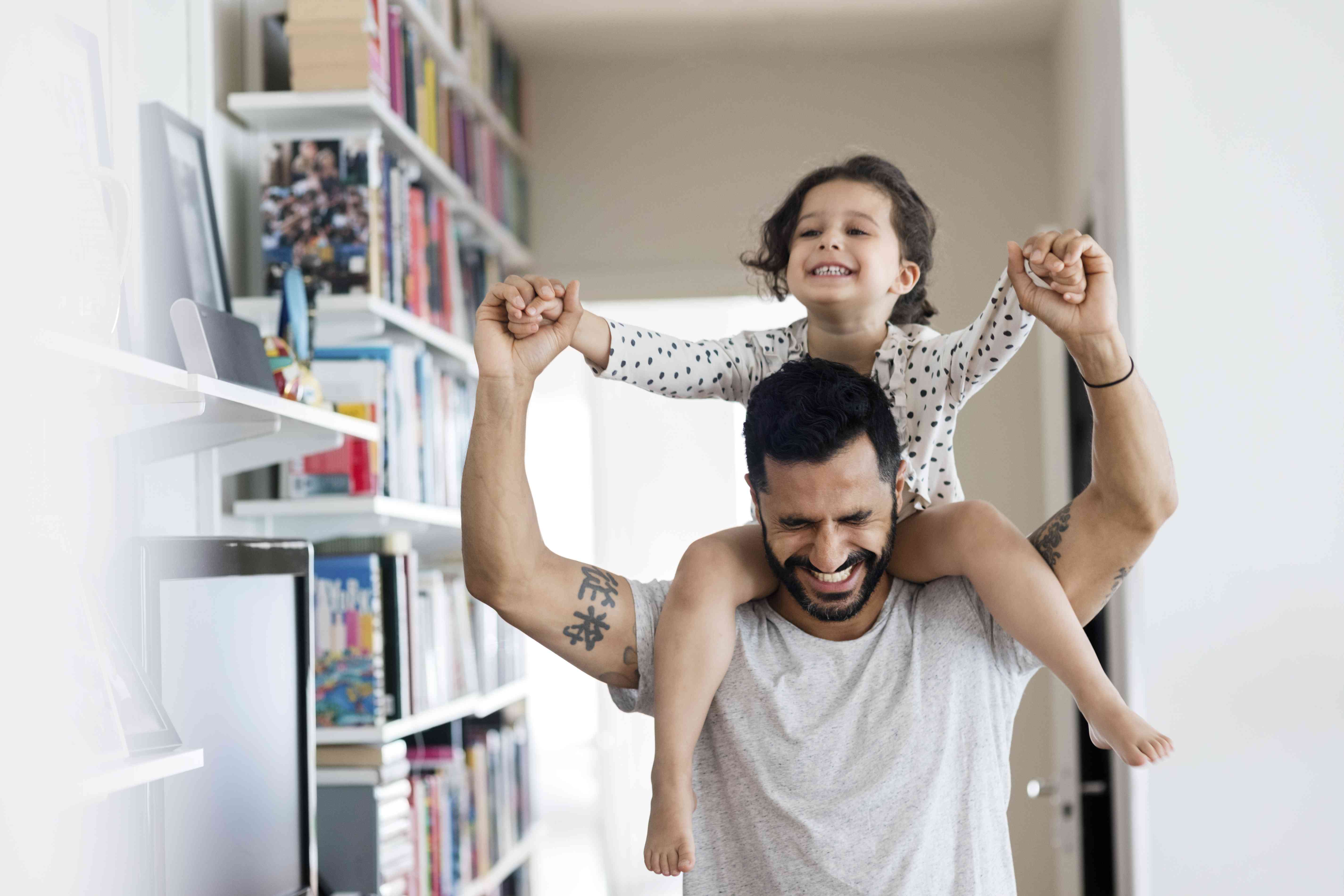 A young adult holds a toddler on his shoulders.