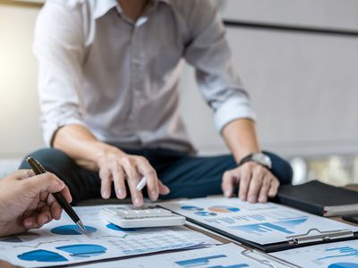 Businessman discussing charts with colleague on table in office.