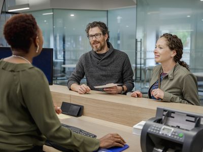 A couple in a bank talks to a teller.